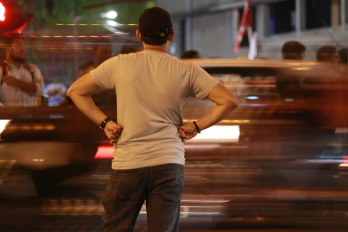 A man standing on a street corner with his hands on his hips