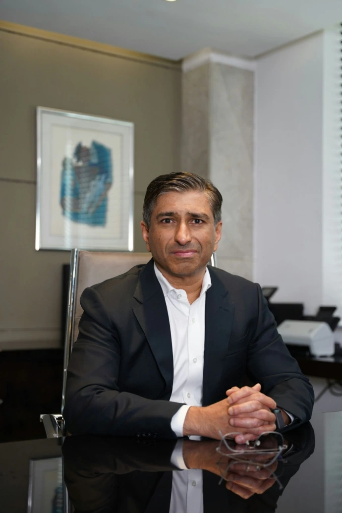 A man in a suit poses in an office.
